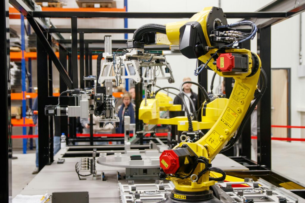 Imagem atual: Close-up of a yellow industrial robotic arm in action at a modern manufacturing facility.